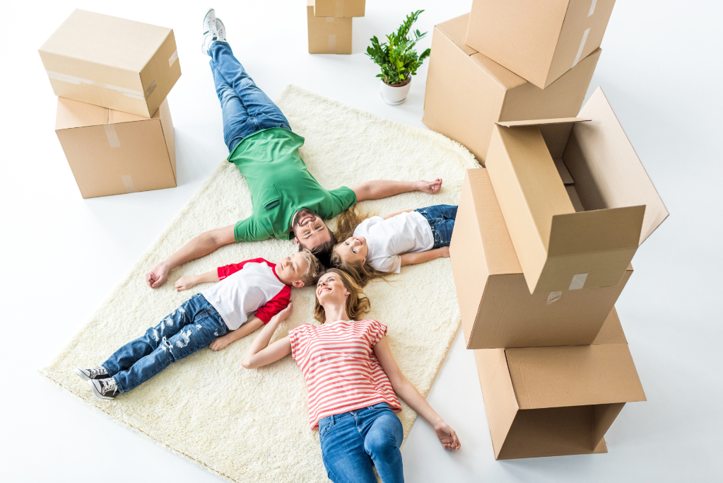 Top view of young family of four relaxing on carpet after moving into new house isolated on white